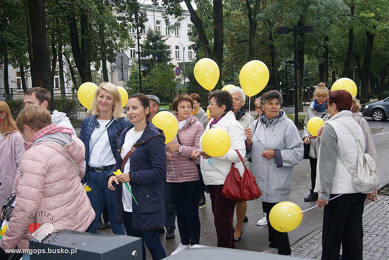 Marsz z cyklu "pomagam sercem" na zdjęciu grupa reprezentująca Klub Seniora z żółtymi balonami zaczynająca marsz na ul Mickiewicza 